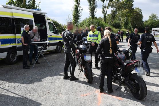 Kontrollstation der Kreispolizei Steinfurt am Parkplatz am Freibad in Lienen. Mehrere Motorräder, Motorradfahrer sowie Polizeibeamte sind zu sehen. 