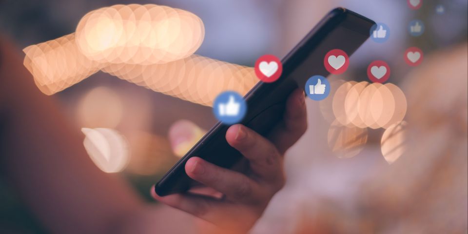 Handy in Hand mit Social Media Icons